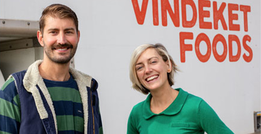 people smiling and posing in front of a truck that reads: Vindeket Foods