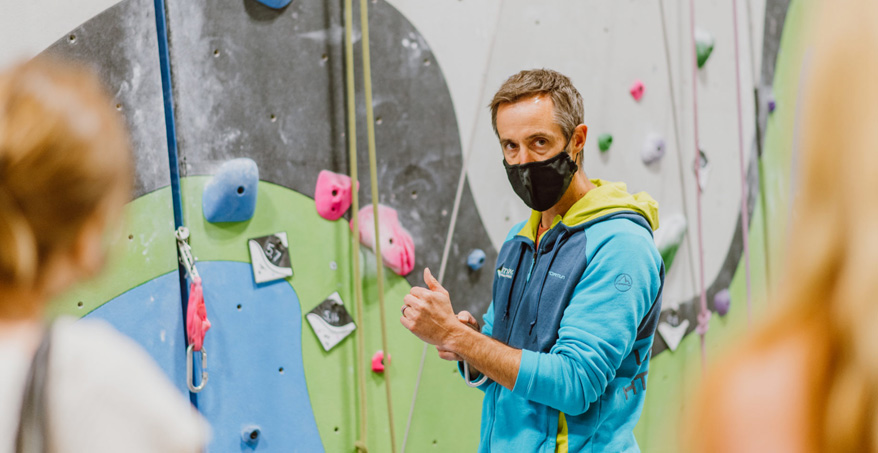 man wearing mask in front of climbing wall